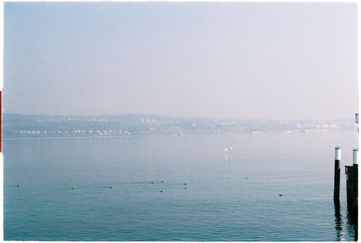 Serene landscape of Lake Constance with distant view of Meersburg, Germany in a calming blue tone.