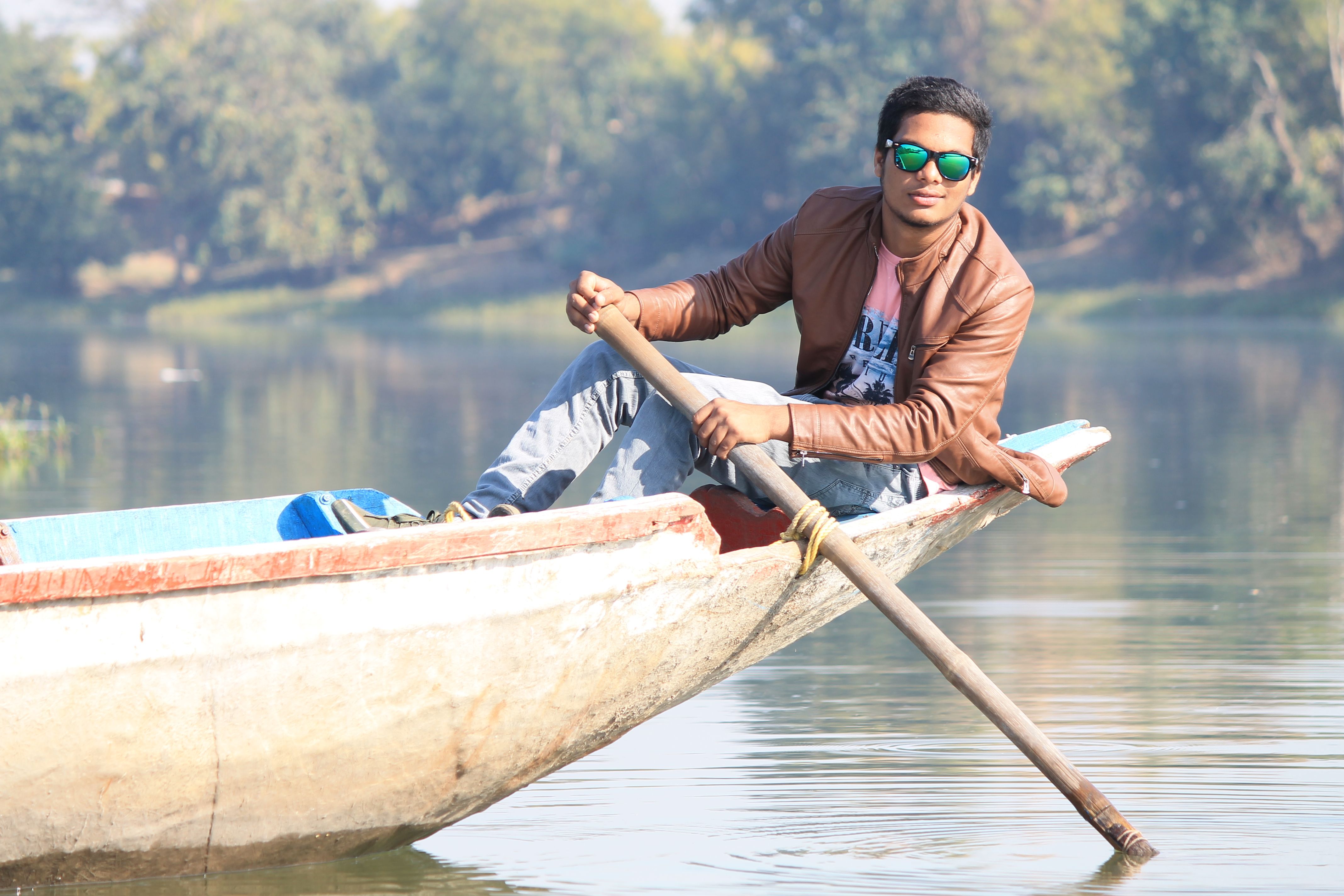 Man rowing a boat on a calm river, enjoying the tranquility and nature.