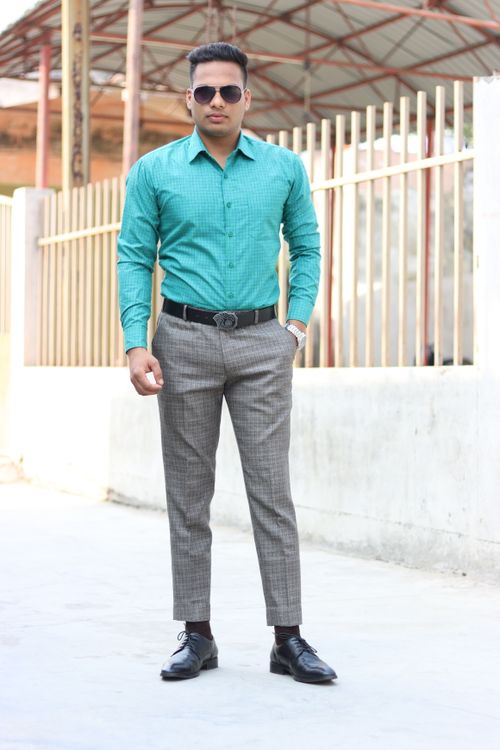 Free Confident man in teal shirt and checked trousers standing outdoors. Fashionable and elegant look. Stock Photo
