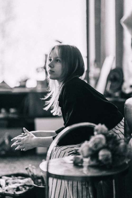 Free A contemplative woman sitting in an artistic black and white home interior setting. Stock Photo