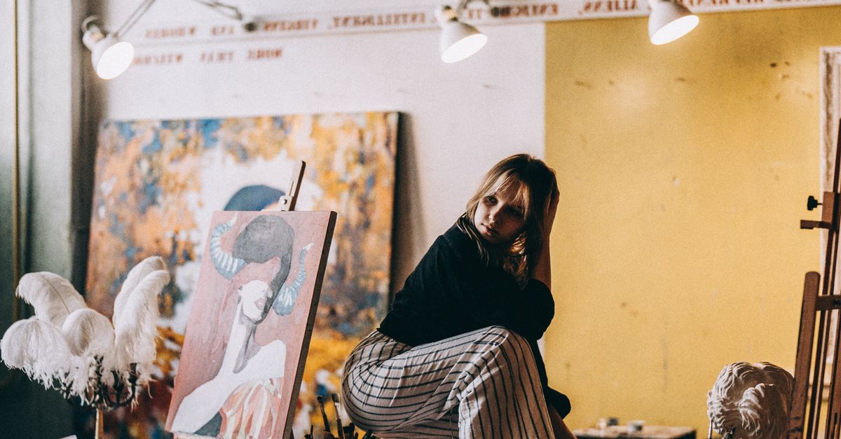 Young Woman Crouching on a Table in an Art Studio · Free Stock Photo