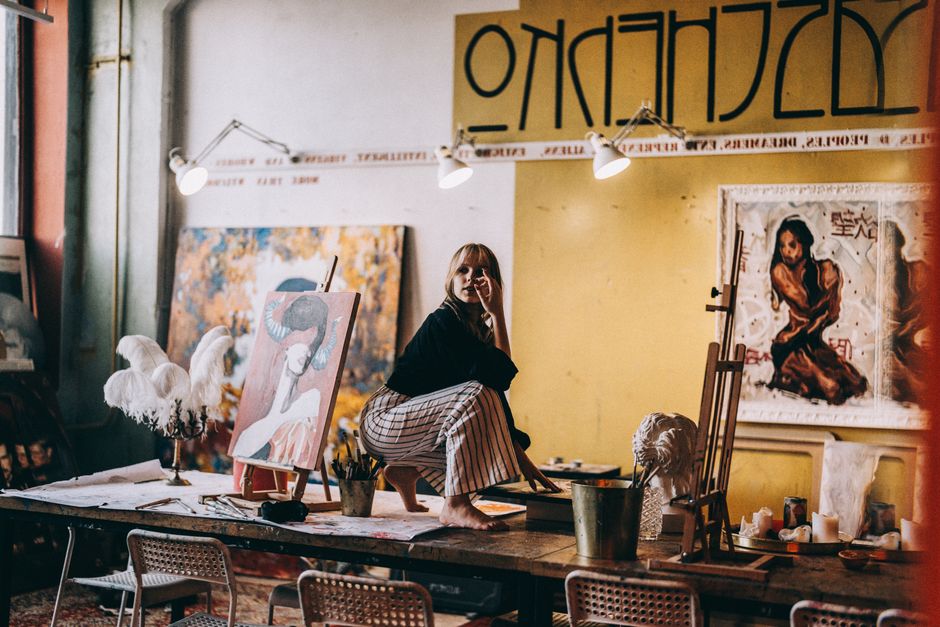 An artist's studio interior within The Arts Factory, featuring vibrant paintings on easels, sculptures, art supplies scattered on workbenches, and natural light streaming through large windows. - las vegas arts district An artist's studio interior within The Arts Factory, featuring vibrant paintings on easels, sculptures, art supplies scattered on workbenches, and natural light streaming through large windows. - las vegas arts district