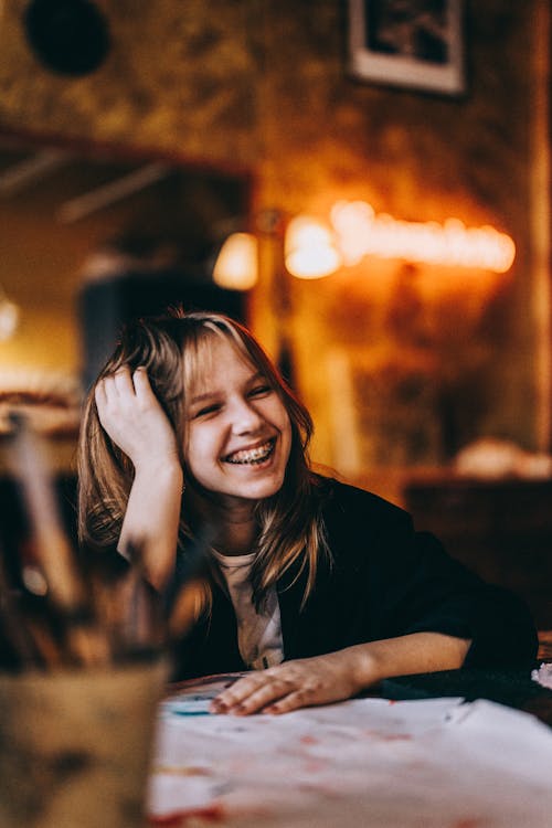 Young Girl with Braces Sitting at a Table and Smiling