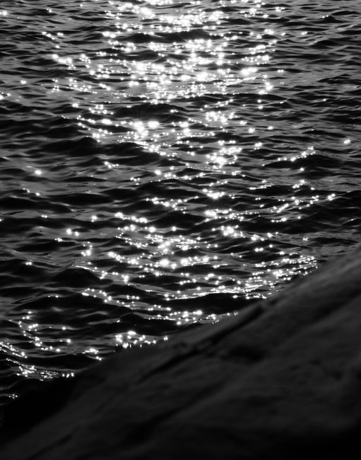 Capture of shimmering ocean waves in black and white during sunset, creating a dramatic scene.