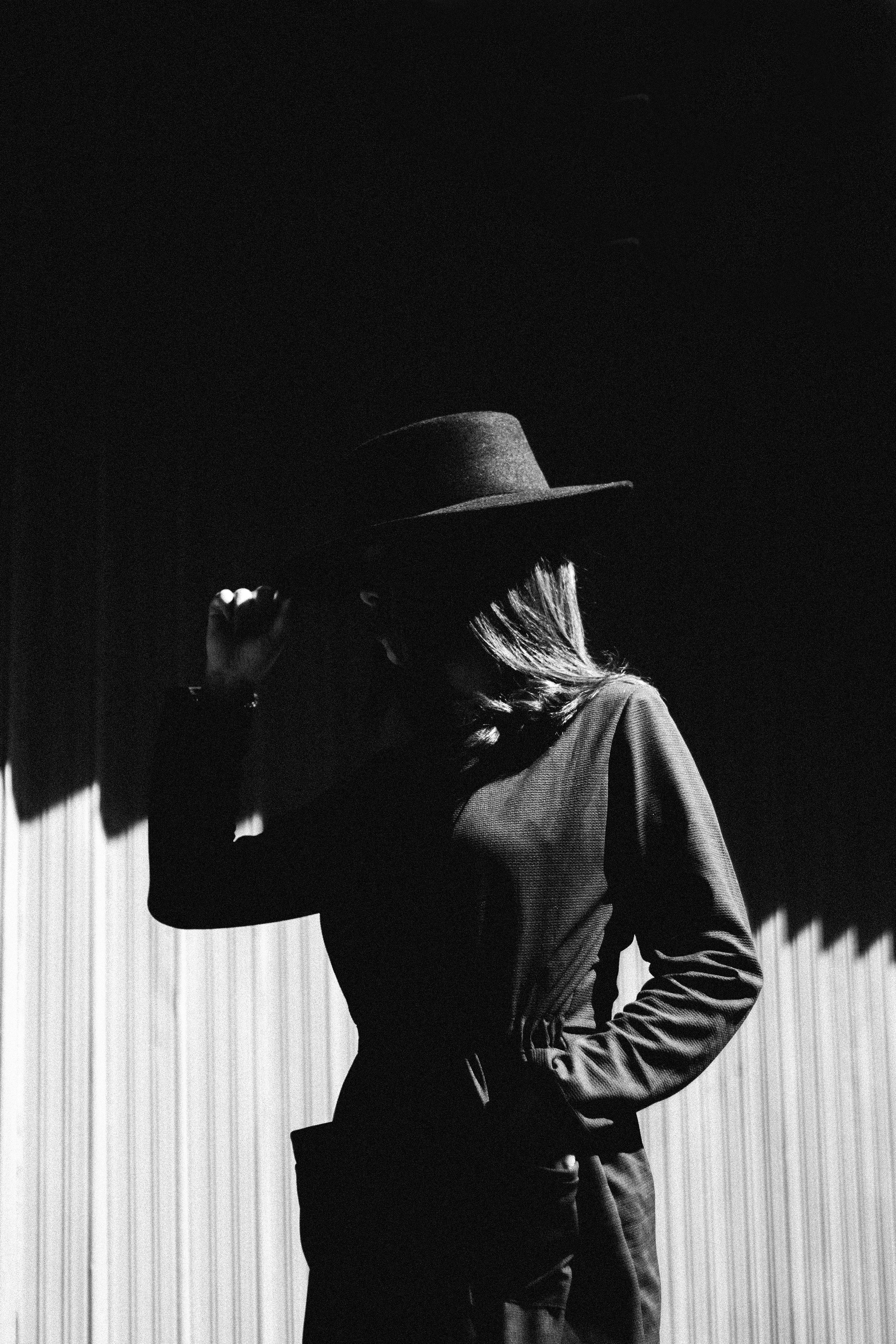 Elegant silhouette of a woman in a black hat, partly obscured in dramatic lighting.