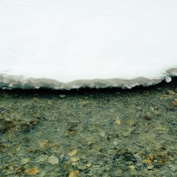 Close-up view of snow meeting a clear, icy body of water during winter.