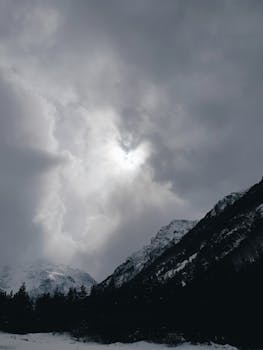 Captivating winter mountain scene with snow-covered peaks and dramatic clouds.
