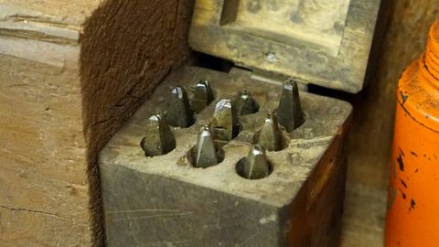 Rustic workshop scene with an open vintage wooden box containing metal tools on a wooden bench.
