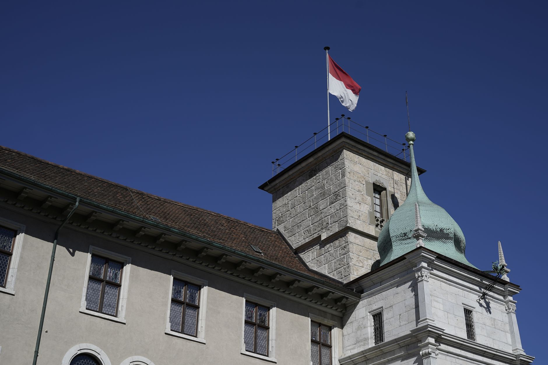 Low angle view of a historic tower with a flag against a clear blue sky in Solothurn, Switzerland.