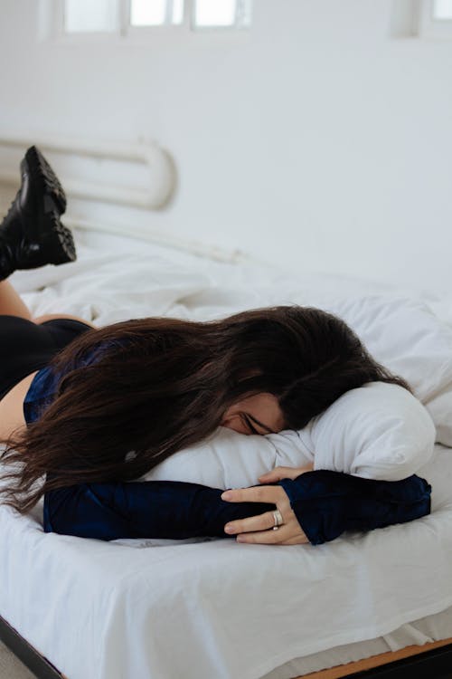 Woman Wearing Boots Lying on a Bad and Cuddling a Cushion