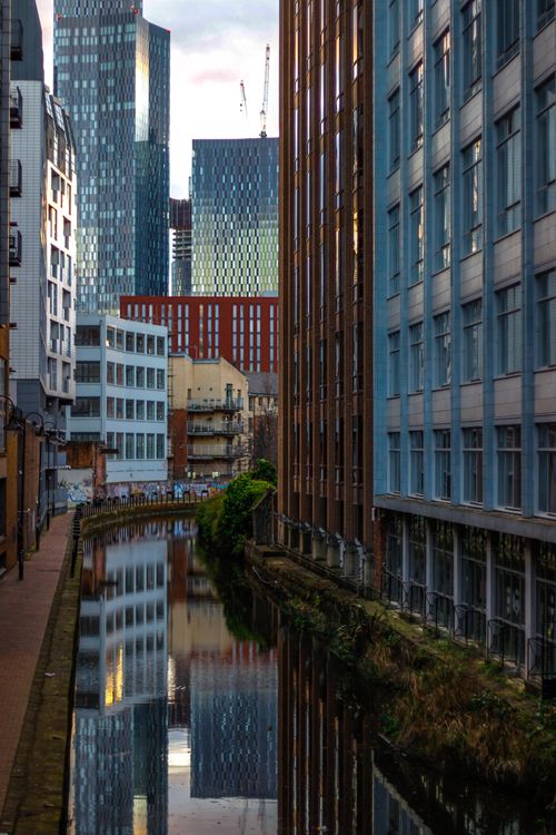 Free A view of Manchester's modern skyline reflecting in a canal, capturing urban architecture. Stock Photo