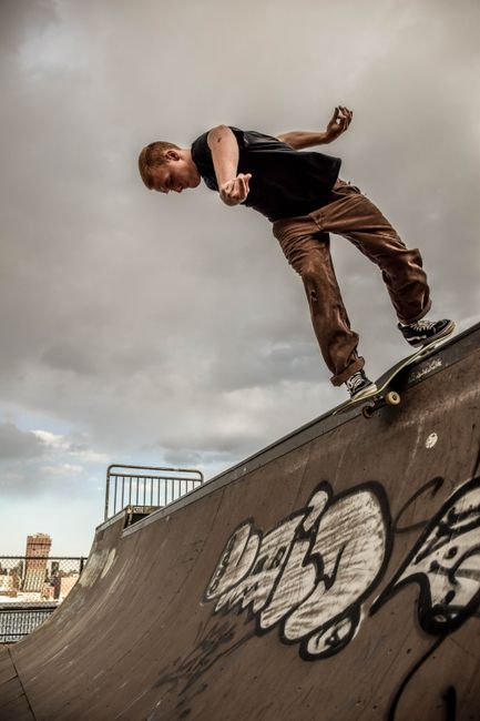 Dynamic shot of a skateboarder balancing on a graffiti-covered ramp under cloudy skies.