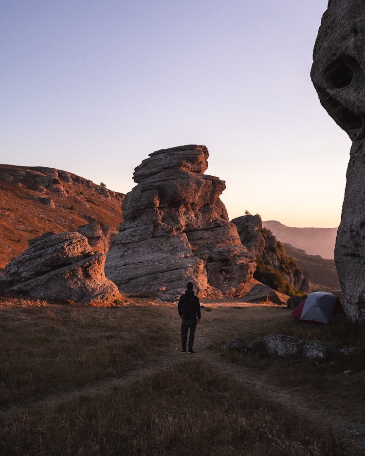 Man Standing In A Camp In Rocky Landscape