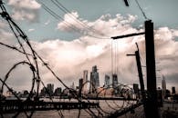 引人注目的城市景观中，摩天大楼的轮廓映衬着戏剧性的天空，铁丝网构成了框架