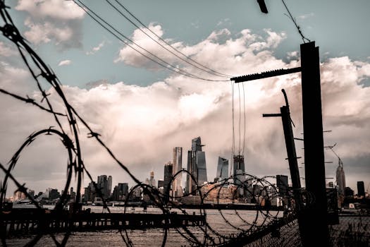 引人注目的城市景观中，摩天大楼的轮廓映衬着戏剧性的天空，铁丝网构成了框架