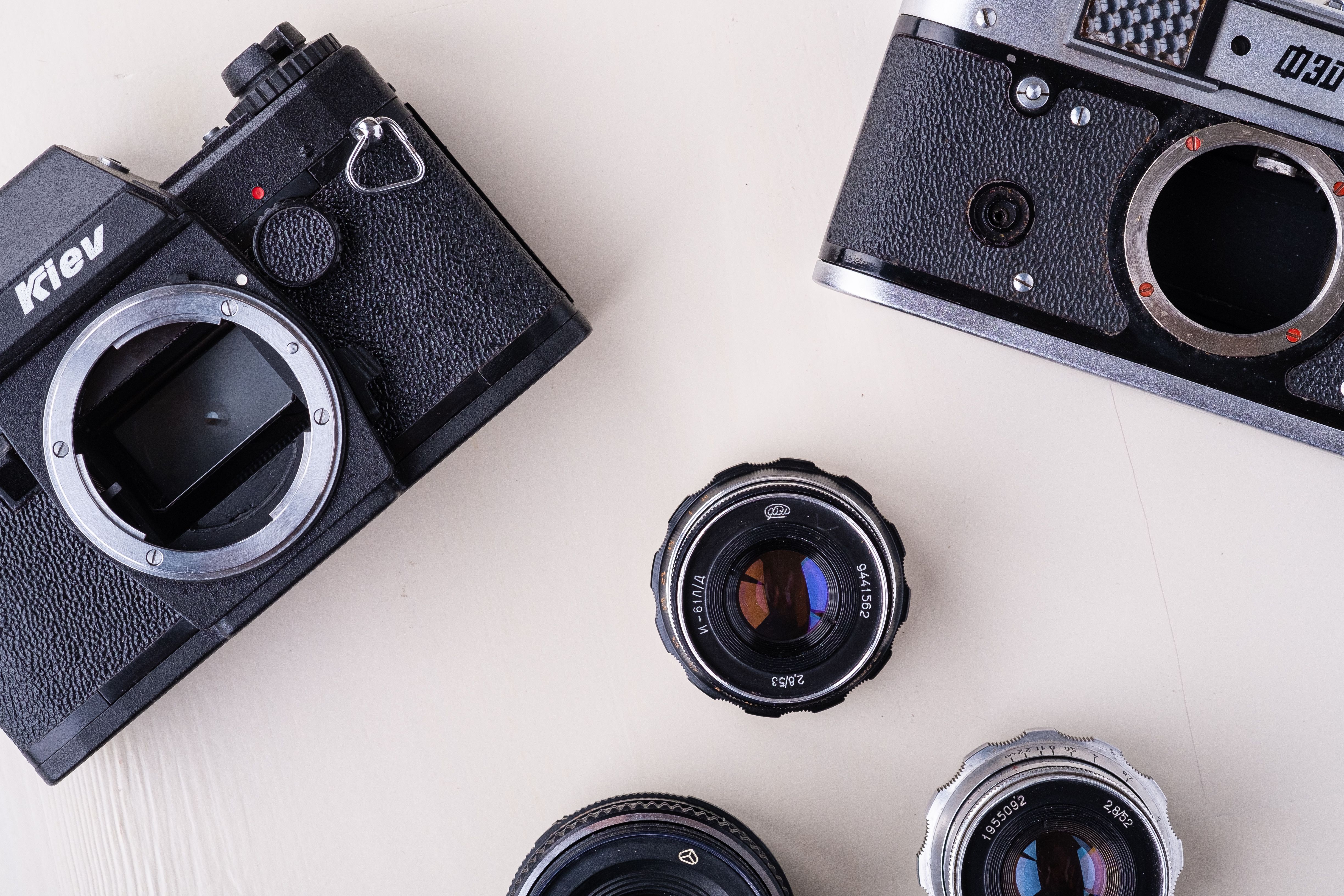 Artistic flat lay of vintage cameras and lenses on a white background, showcasing classic photography gear.