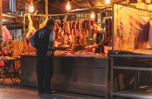 Man Shopping at a Butchers Stand in the Market 