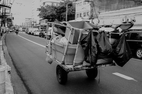 Free A black and white photo of an overloaded cart on a busy city street, reflecting urban life. Stock Photo