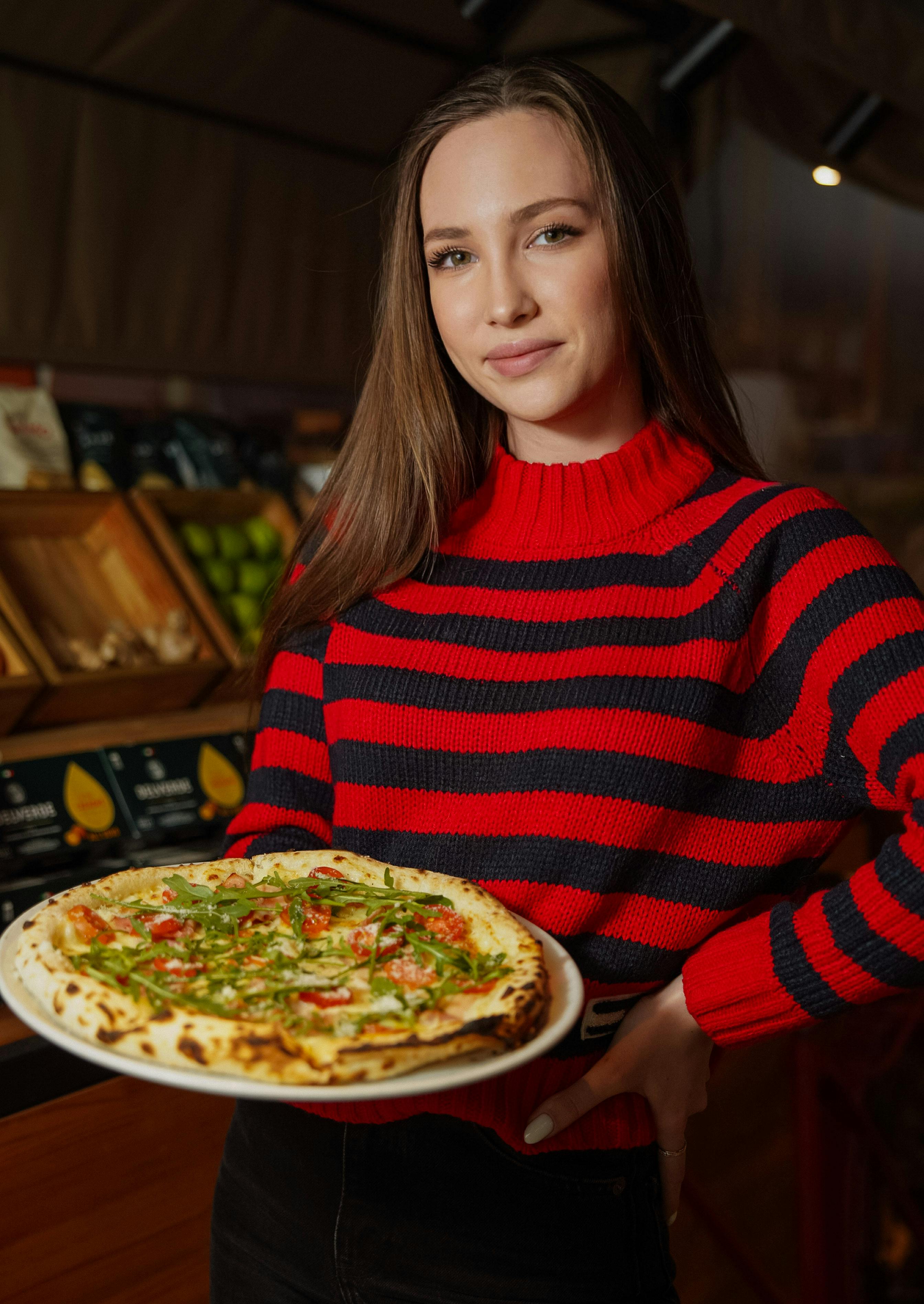 Lady holding a fresh baked pizza