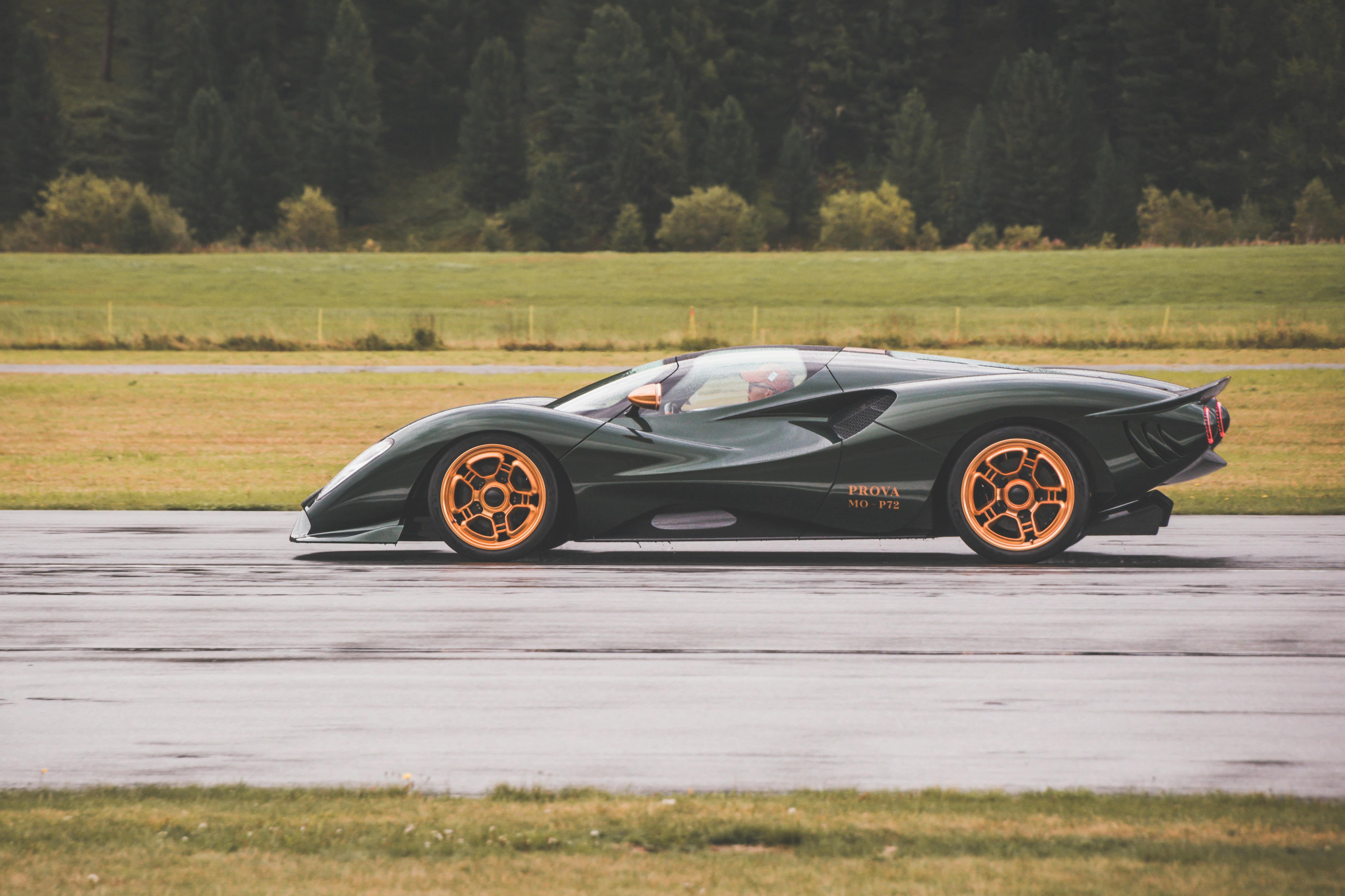 A green and orange sports car driving on a wet road
