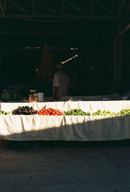 Fresh vegetables and fruits on a sunlit market stall in Datça, Türkiye.