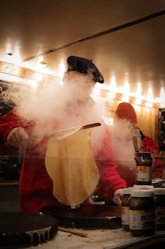 A chef prepares delicious French crepes at a vibrant Hamburg food market, surrounded by steam and warm lighting.