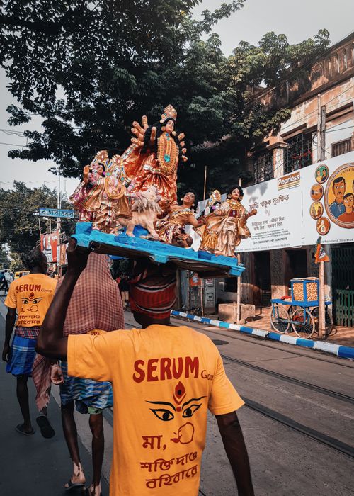 Free Street parade in Kolkata featuring people carrying Hindu deity figurines, vibrant cultural scene. Stock Photo