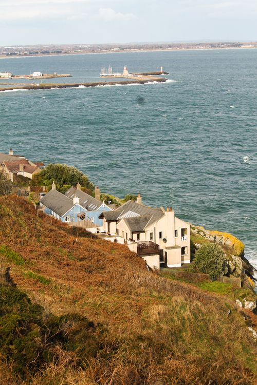 Free Beautiful aerial view of Howth's coastline with houses, pier, and sea in Ireland. Stock Photo