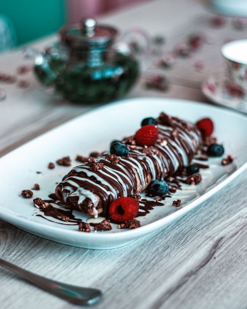 Free Close-up of a chocolate dessert garnished with berries on a plate, photographed indoors. Stock Photo