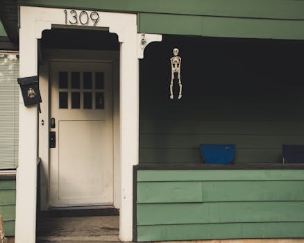 一座绿色房屋的门廊上，挂着一扇门，门上装饰着万圣节骨架