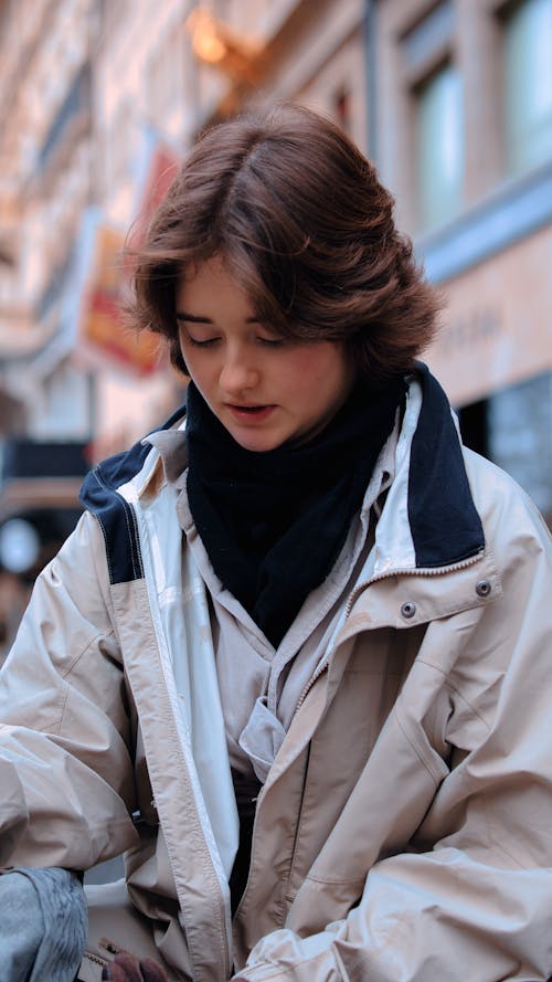 Young Woman in a White Nylon Jacket on the Sidewalk