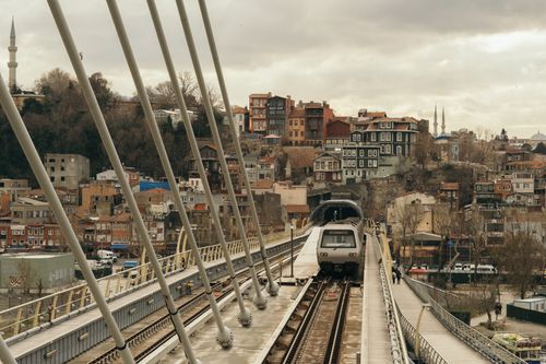Free Train crossing a modern bridge in Istanbul with historic houses in the background. Stock Photo
