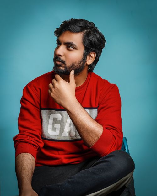 Free Portrait of a thoughtful man in red sweater with a blue backdrop. Stock Photo