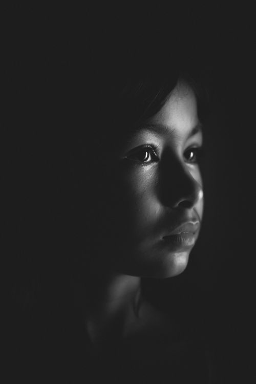Free A striking black and white portrait capturing a child's thoughtful gaze in soft lighting. Stock Photo