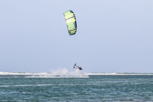 Free Dynamic kiteboarding action with a man soaring over ocean waves, showcasing summer vibes. Stock Photo
