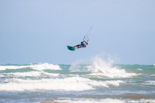 Free Exciting kitesurfing stunt showcasing athleticism and skill against the backdrop of ocean waves. Stock Photo