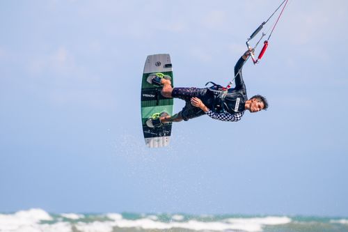 Free Man skillfully kitesurfing midair over ocean waves, capturing thrilling water sport action. Stock Photo