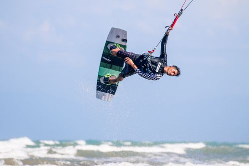 Free A man performing a stunning aerial trick while kitesurfing in the ocean on a sunny day. Stock Photo