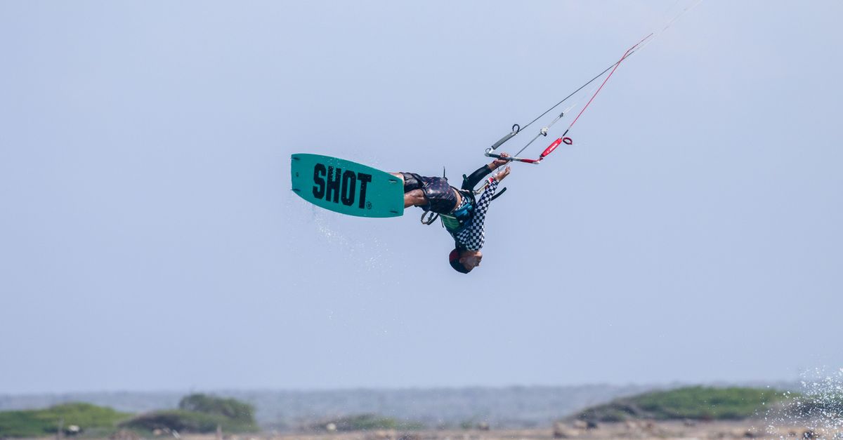 Action-packed kitesurfing captured mid-air against a scenic ocean backdrop.