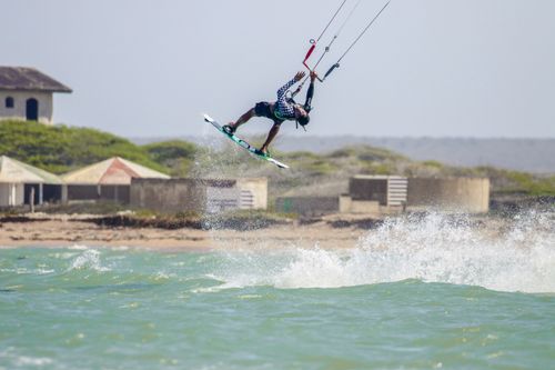 Free A kitesurfer performing a trick midair with splashing water in an outdoor setting, showcasing skill and adventure. Stock Photo