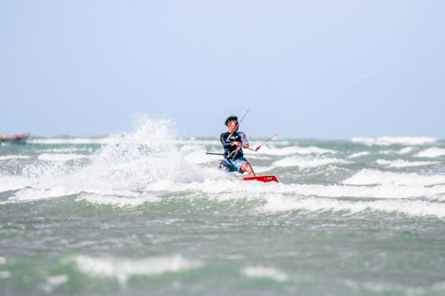 Free Man kitesurfing over ocean waves on a clear sunny day, showcasing skill and adventure. Stock Photo