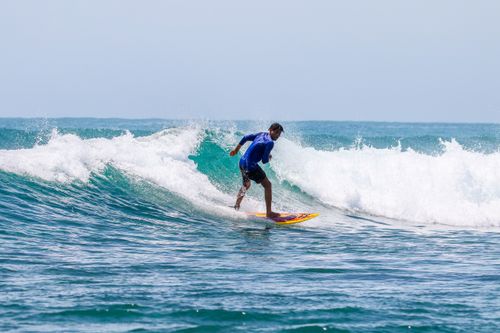 Free A surfer in blue rash guard skillfully riding the ocean waves on a sunny day. Stock Photo