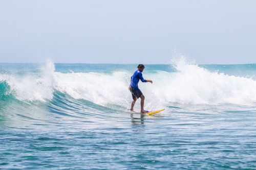 Free Man surfing on ocean wave with blue sky, enjoying summer beach activity. Stock Photo