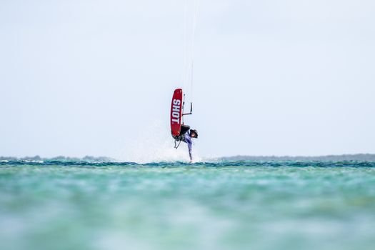 Thrilling kitesurfing jump captured midair over turquoise ocean waters.