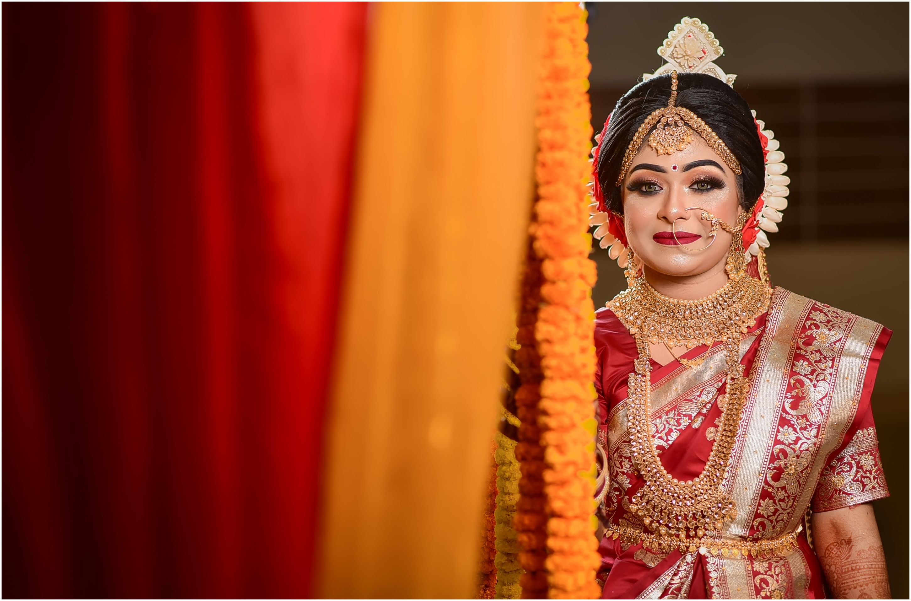 A smiling Indian bride in ornate traditional attire with jewelry and embroidery for a cultural wedding.