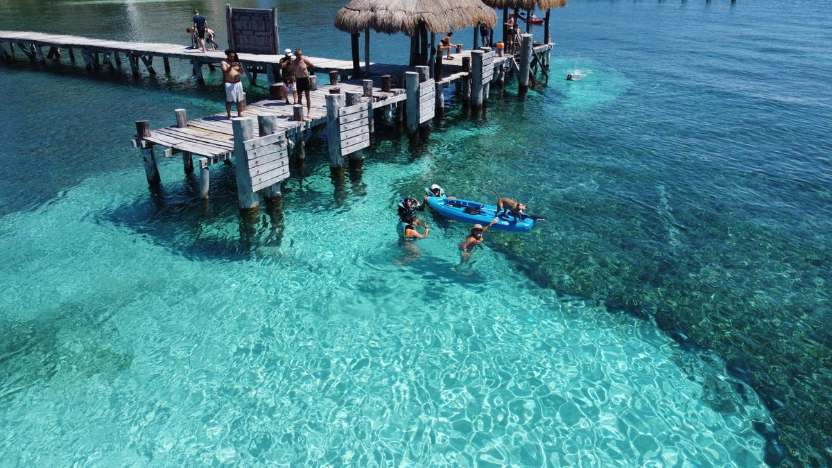 People enjoying a sunny day at Isla Mujeres pier with clear water and vibrant sc
