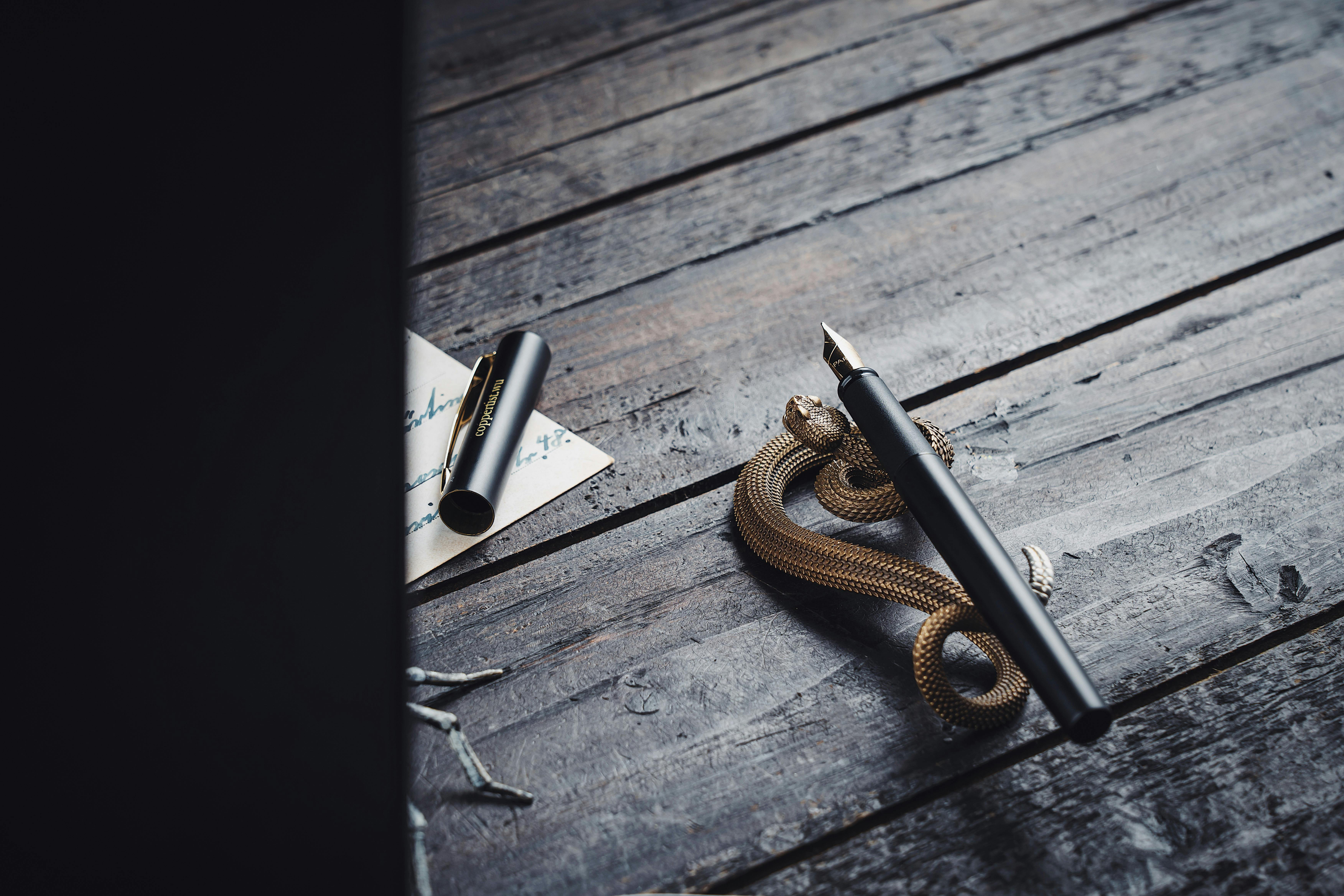 A vintage fountain pen elegantly displayed on a wooden desk with a decorative snake holder.