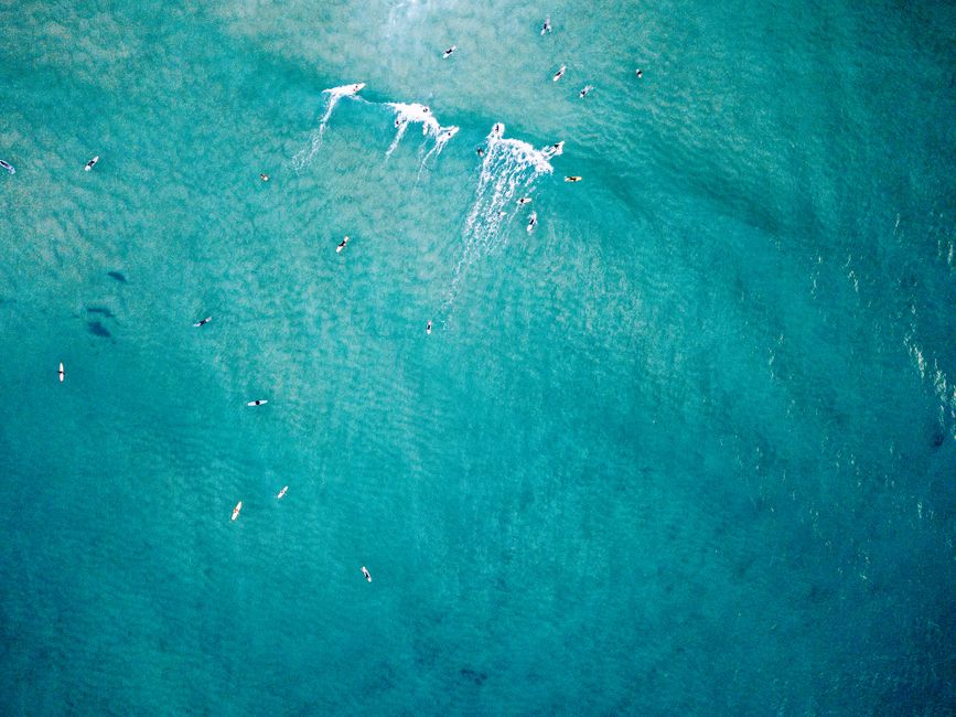 Drone shot of surfers riding waves at Burleigh Heads, Queensland, Australia.