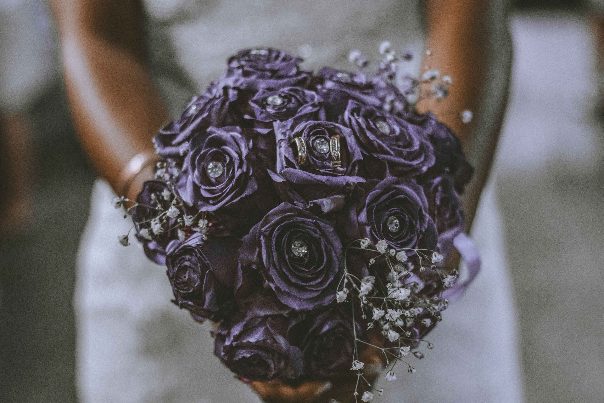 Bride holding a bouquet of purple flowers in soft morning light