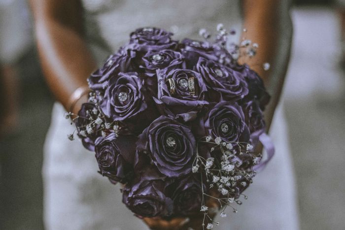 Bride holding a bouquet of purple flowers in soft light